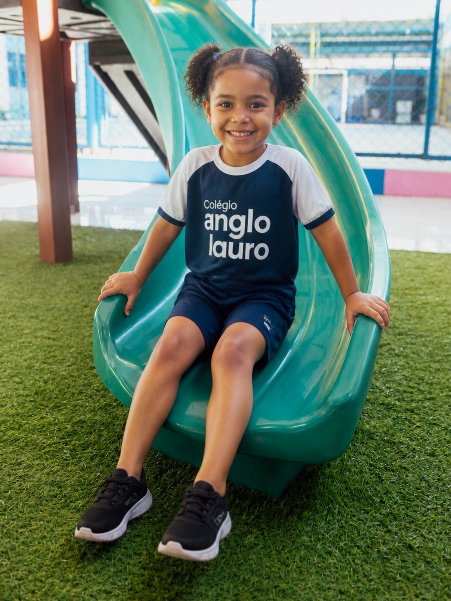 Aluna da Educação Infantil sorrindo no escorregador do playground do Colégio Anglo Lauro